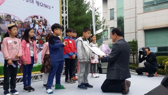 무릎 꿇은 어른, 초등시상을 위해 생명종합사회복지관 배영길 관장이 눈높이를 맞추고 있다